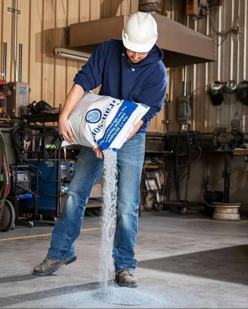 Oil absorbent granuels being used to clean a spillage in a warehouse.