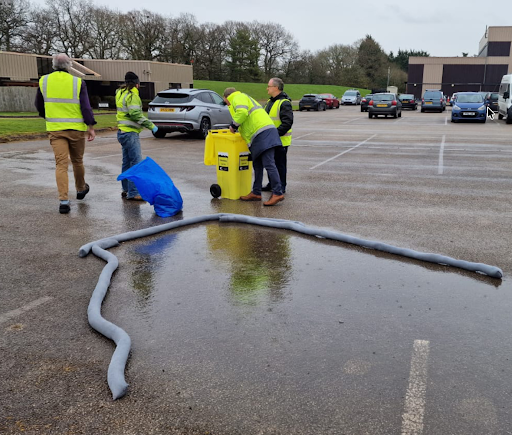 Spill response training session demonstrating the use of Absorbent Granules and spill control materials in a workplace environment.