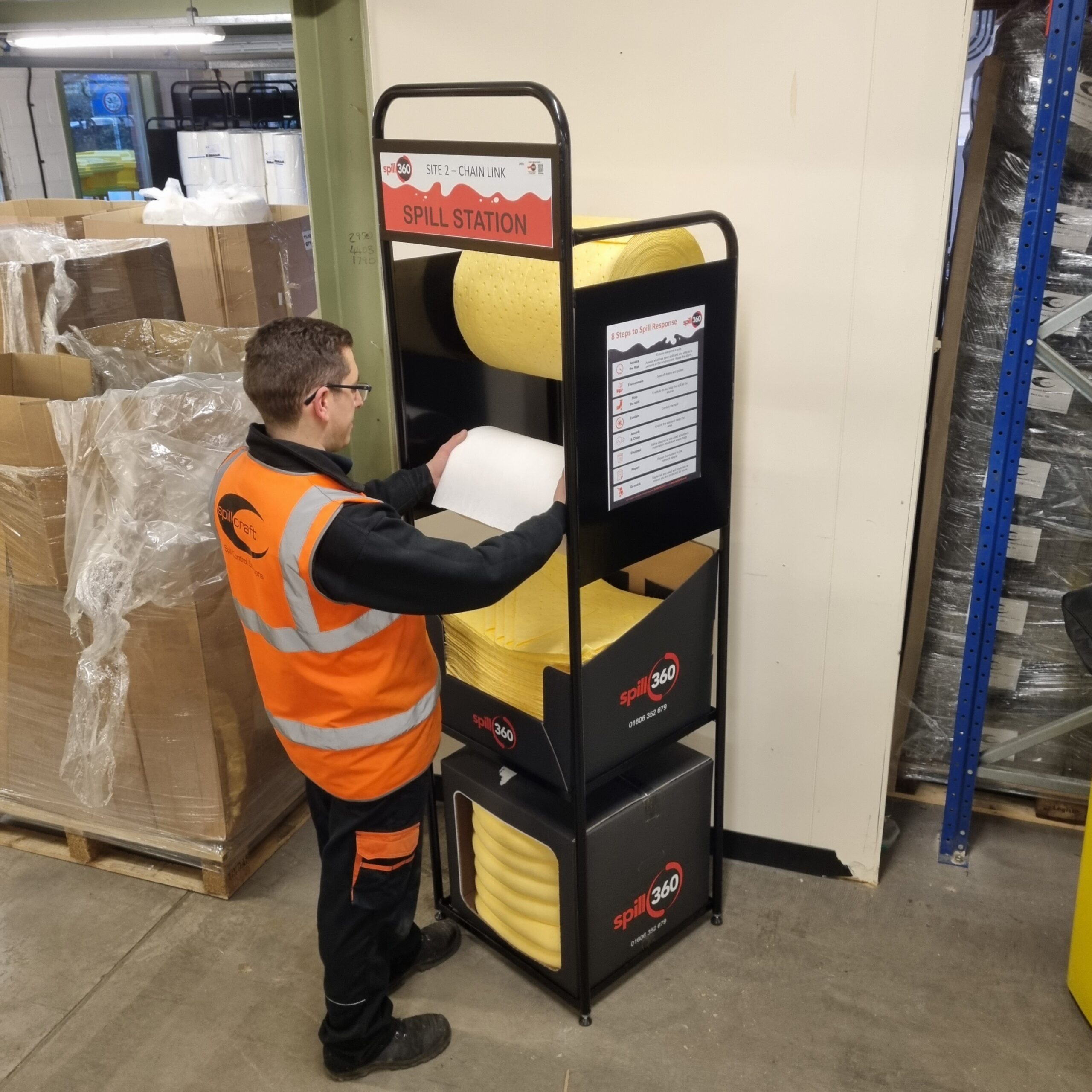 Worker accessing absorbent pads and spill response supplies from a spill station demonstrating different types of absorbent materials.
